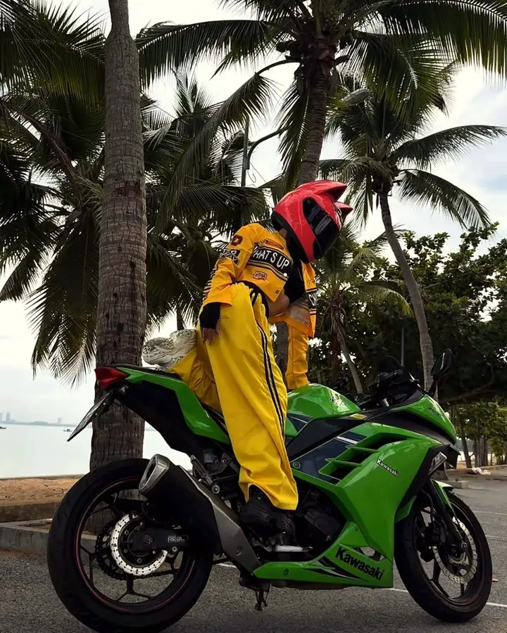 Rider in a helmet with a green Kawasaki Ninja by the sea
